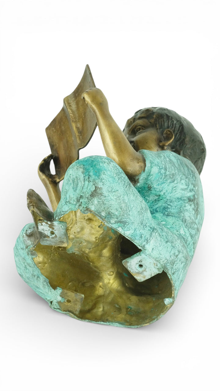 Escultura de bronce de un joven sentado leyendo un libro