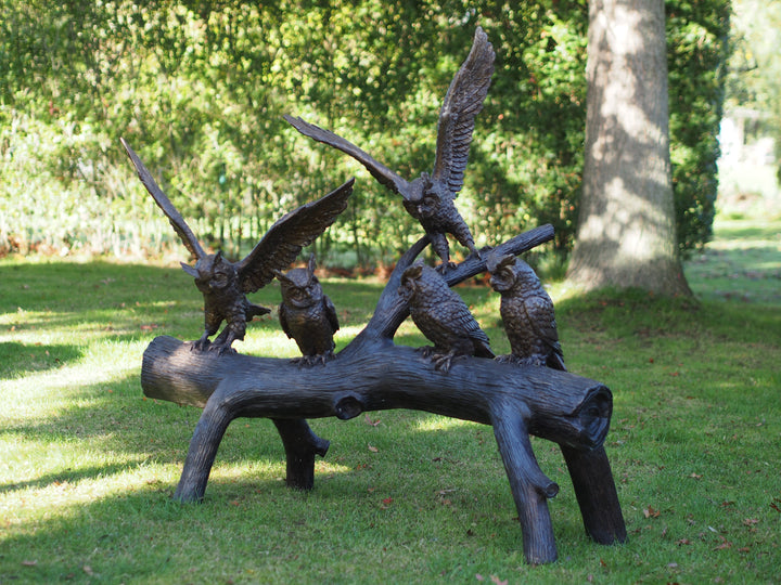 Large bronze sculpture of a group of owls on a tree trunk