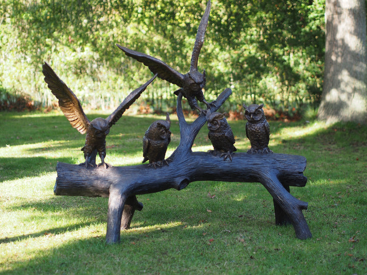 Large bronze sculpture of a group of owls on a tree trunk