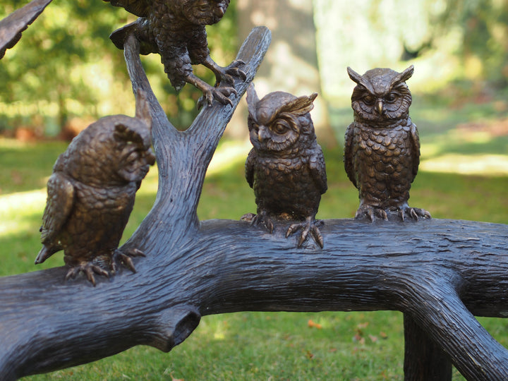 Large bronze sculpture of a group of owls on a tree trunk
