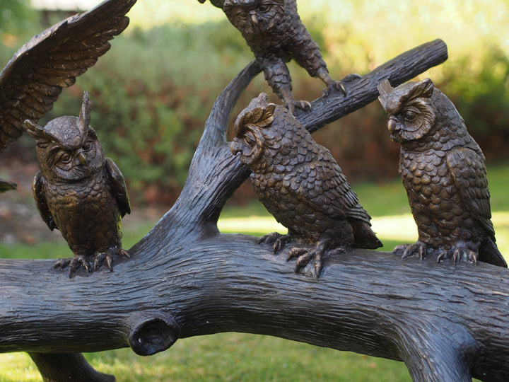 Large bronze sculpture of a group of owls on a tree trunk