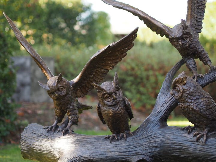 Large bronze sculpture of a group of owls on a tree trunk
