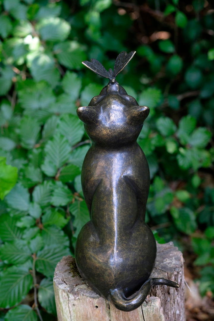 Bronze sculpture of a curious cat gazing at a butterfly, enhancing garden charm and elegance.