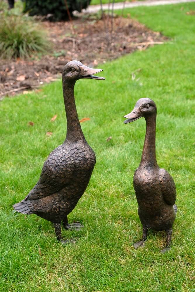 Bronze duck family sculptures in a garden setting, depicting a mother and father duck. Perfect outdoor decoration.