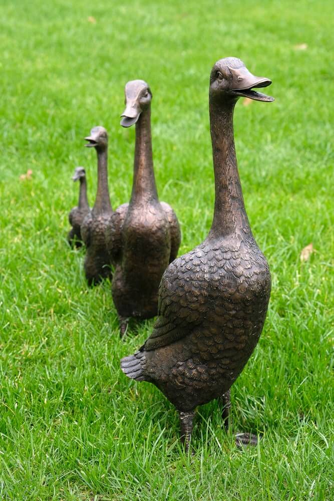Set of 4 bronze duck family sculptures on green grass, perfect for outdoor garden decoration.