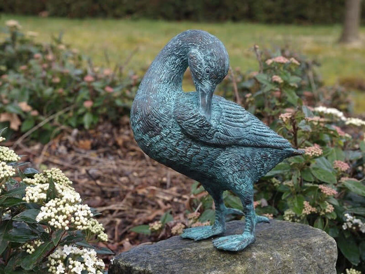 Bronze duck sculpture cleaning its feathers in a garden setting, adding charm to outdoor spaces.