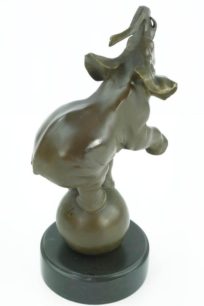 Bronze sculpture of an elephant balancing on a ball, mounted on a round marble base, signed 'Milo'. Height: 33 cm.