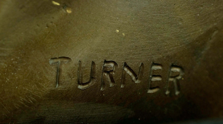 Close-up of the signature 'Turner' on a bronze horse head sculpture.