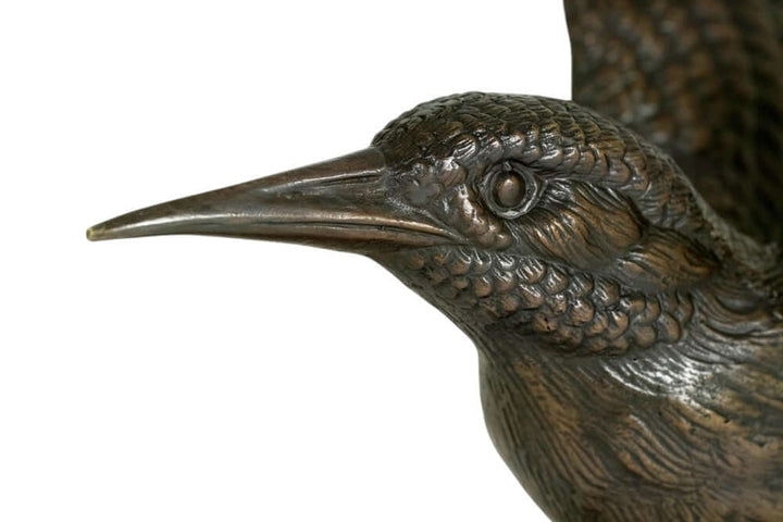 Close-up of a bronze kingfisher sculpture, showcasing detailed feathers and lifelike expression.