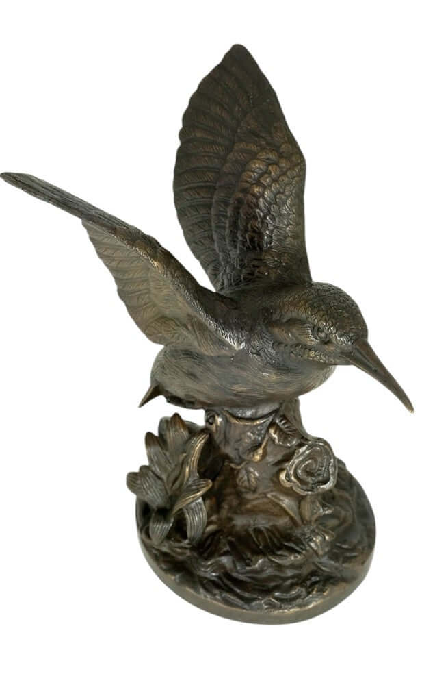 Bronze king fisher sculpture with wings spread, perched on detailed floral decorated tree trunk.