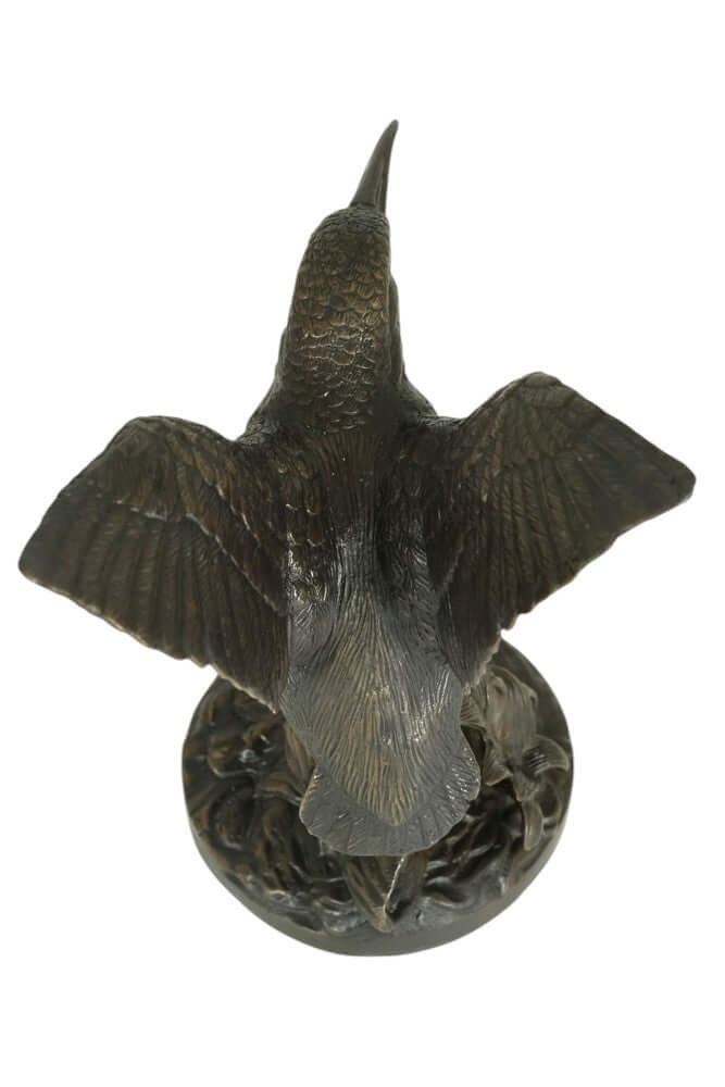 Detailed bronze kingfisher sculpture with wings spread, showcasing floral decoration on a tree trunk.