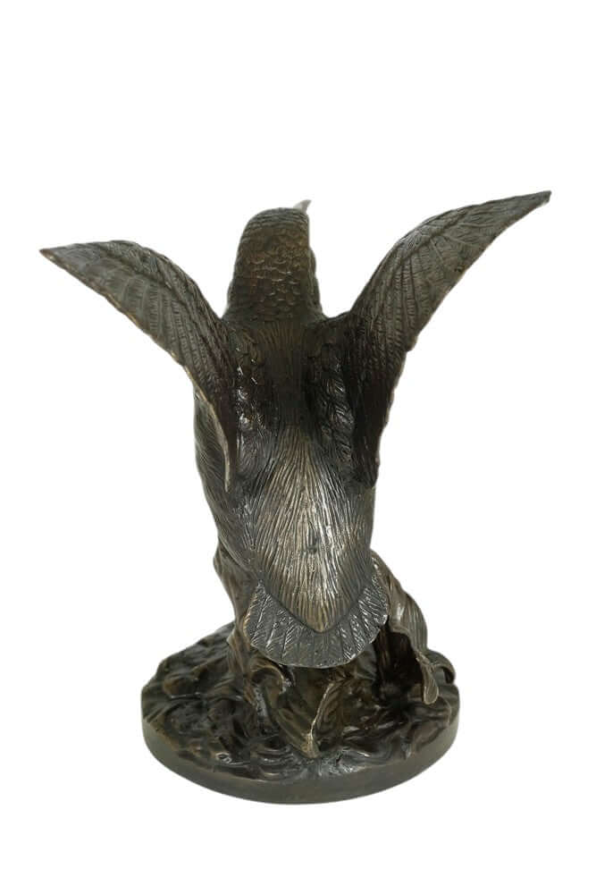 Bronze sculpture of a king fisher with wings spread, detailed design on a tree trunk base, warm brown patina.