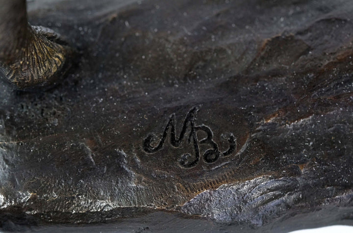Close-up of the signature 'MB' on the base of a bronze moose sculpture, showcasing the artist's detail.