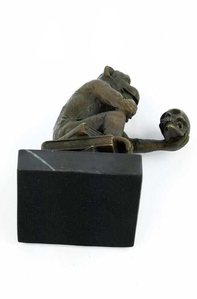 Bronze monkey sculpture holding a skull, symbolizing philosophy, mounted on a black marble base.