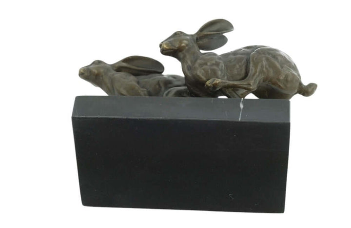 Bronze sculpture of two running hares mounted on a marble base, showcasing dynamic action and fine craftsmanship.