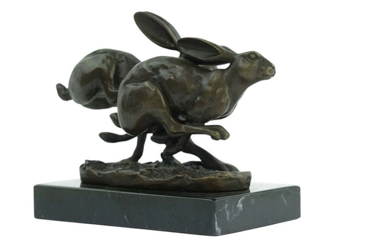 Bronze sculpture of two running hares on marble base, signed by Nick, showcasing dynamic action and artistry.