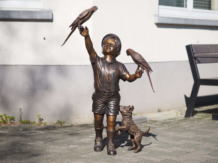 Adorable bronze sculpture of a boy playing with parakeets and a dog, showcasing childhood innocence and joy.