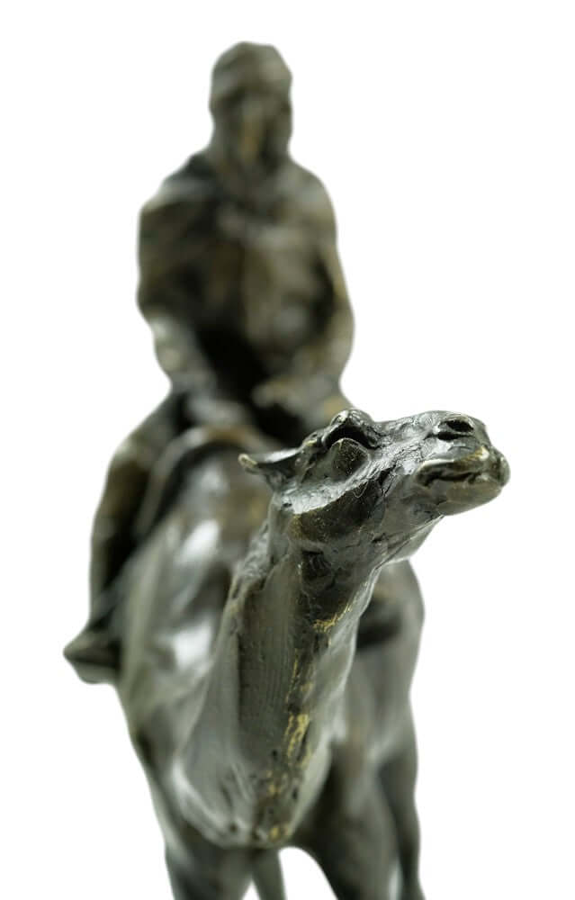 Close-up of a bronze camel sculpture with a rider, showcasing intricate details and artistry.