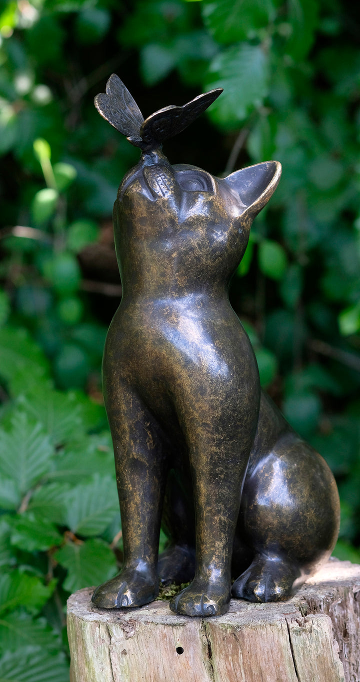 Bronze sculpture of a curious cat with butterfly on nose, perfect for home or garden decor.