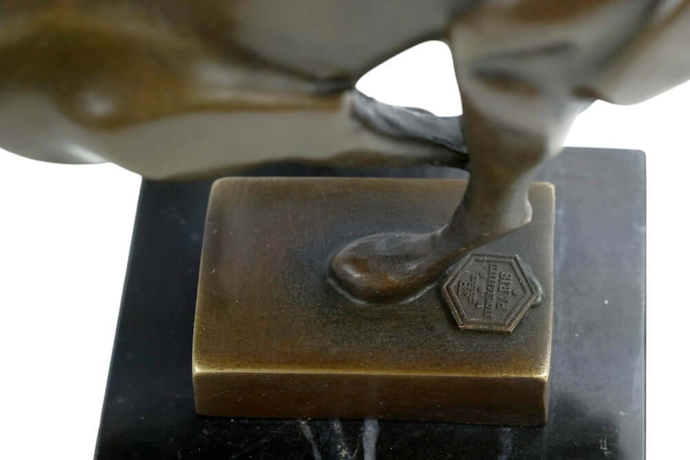 Close-up of the foundry stamp on the base of a bronze sculpture of a cheetah in motion.