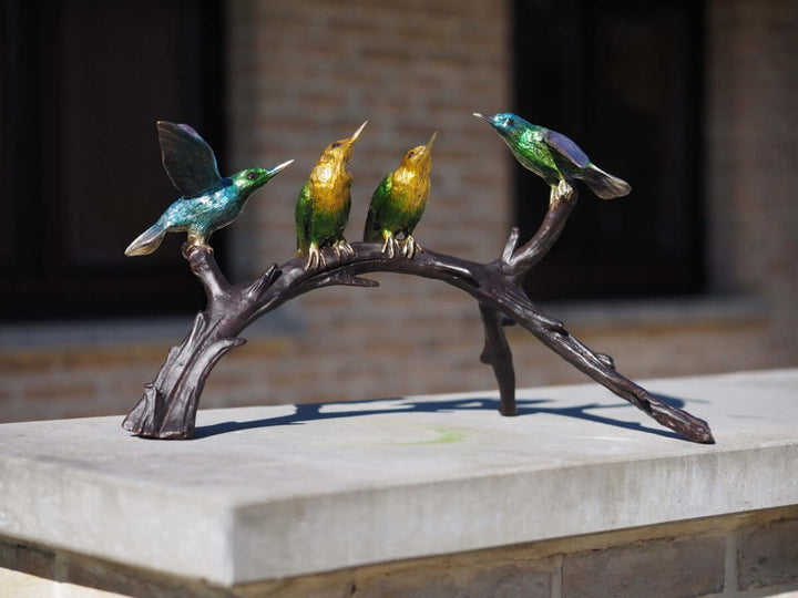 Bronze sculpture of four colorful hummingbirds perched on a branch, perfect for indoor and outdoor decor.