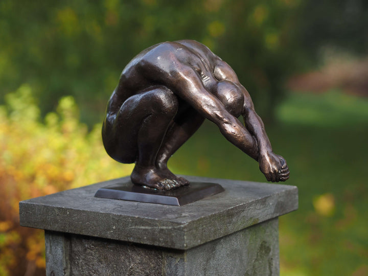 Bronze sculpture of a crouching man with outstretched arms, representing balance and peace, perfect for indoor or outdoor display.