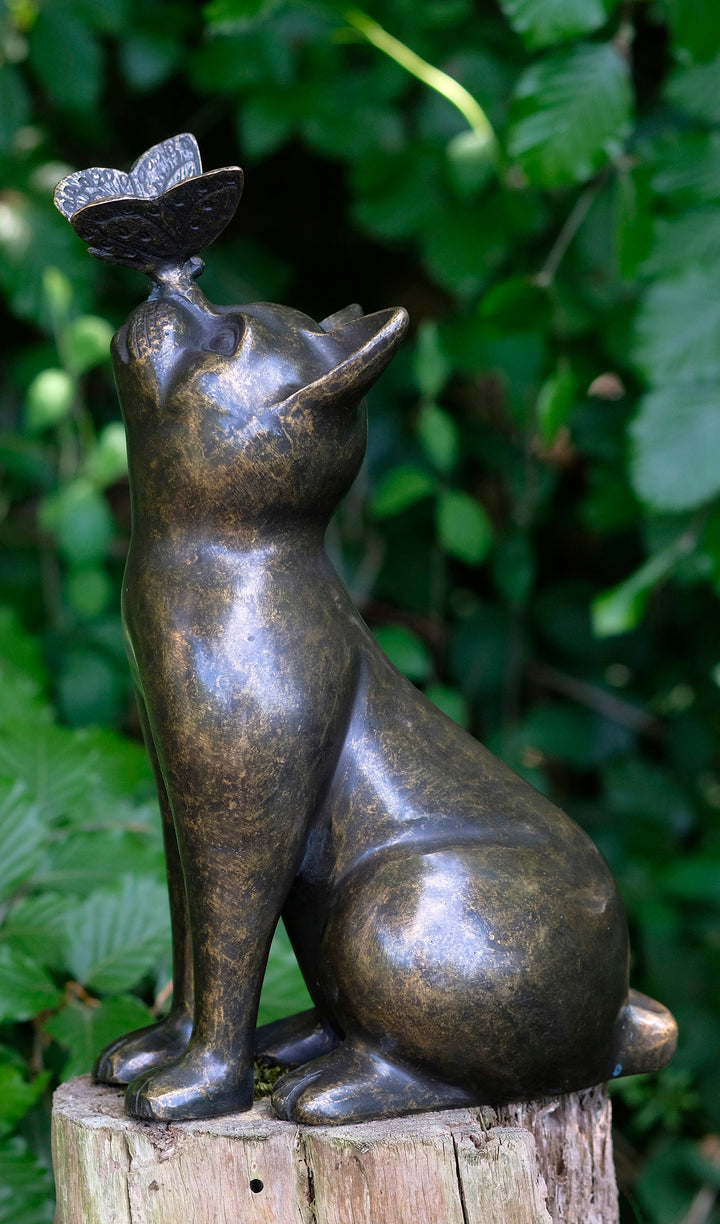 Bronze sculpture of a cat gazing at a butterfly, adding charm to home or garden decor.