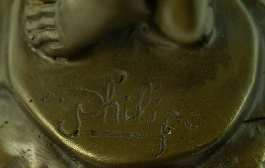 Close-up of the signature 'Philippe' on a bronze sculpture, showcasing the artist's craftsmanship and detail.