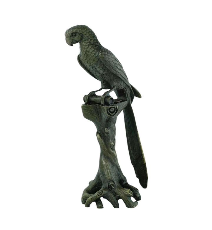 Detailed bronze macaw sculpture perched on a tree trunk, showcasing a rich patina and fine craftsmanship.