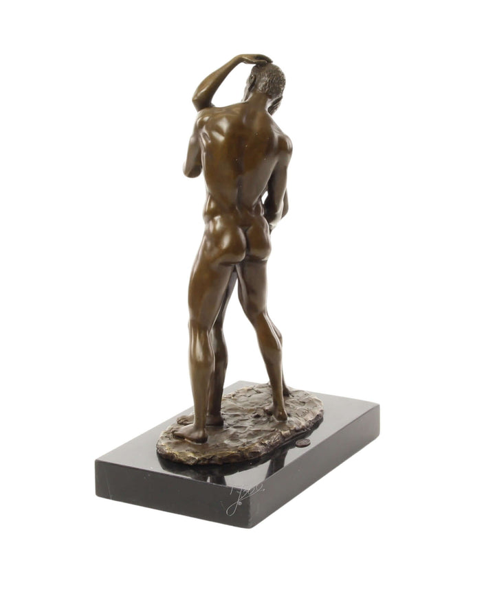 Bronze sculpture of a nude male figure displayed on a marble base, depicting intimacy and sensuality.