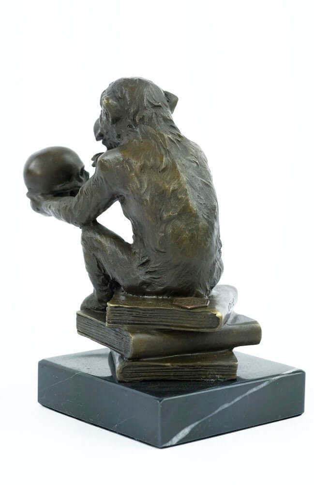 Bronze sculpture of a monkey holding a skull, seated on books, symbolizing philosophy and wisdom.