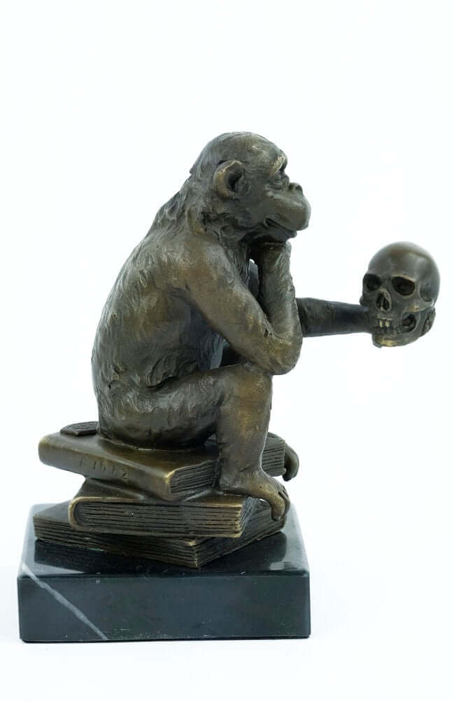 Bronze monkey sculpture holding a skull, sitting on books, symbolizing philosophy and contemplation.