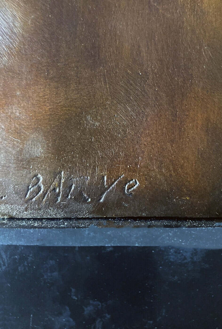 Close-up of a signature on a bronze sculpture, showing intricate details of the artist's mark.