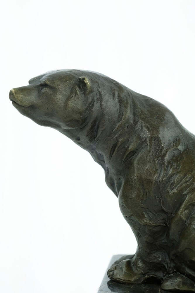 Close-up view of a bronze sculpture of a sitting bear with detailed warm brown patina on a marble base.