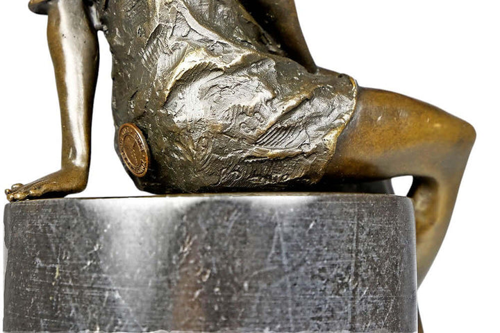 Detailed view of a bronze sculpture of a sitting female in a flimsy dress, mounted on a marble base.
