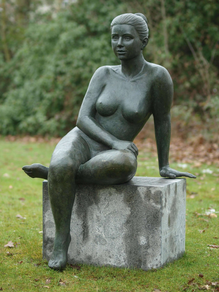 Elegant bronze sculpture of a nude female sitting on a stone base, perfect for garden display.