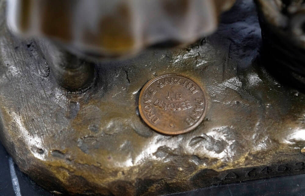 Close-up of the foundry stamp on a bronze sculpture of a girl harvesting grapes, showcasing craftsmanship details.