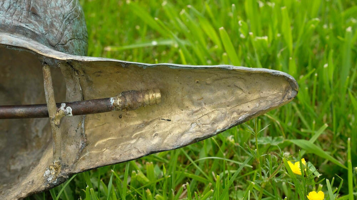 Close-up of the bronze snail sculpture fountain's base, showcasing intricate details and water pipe connection.