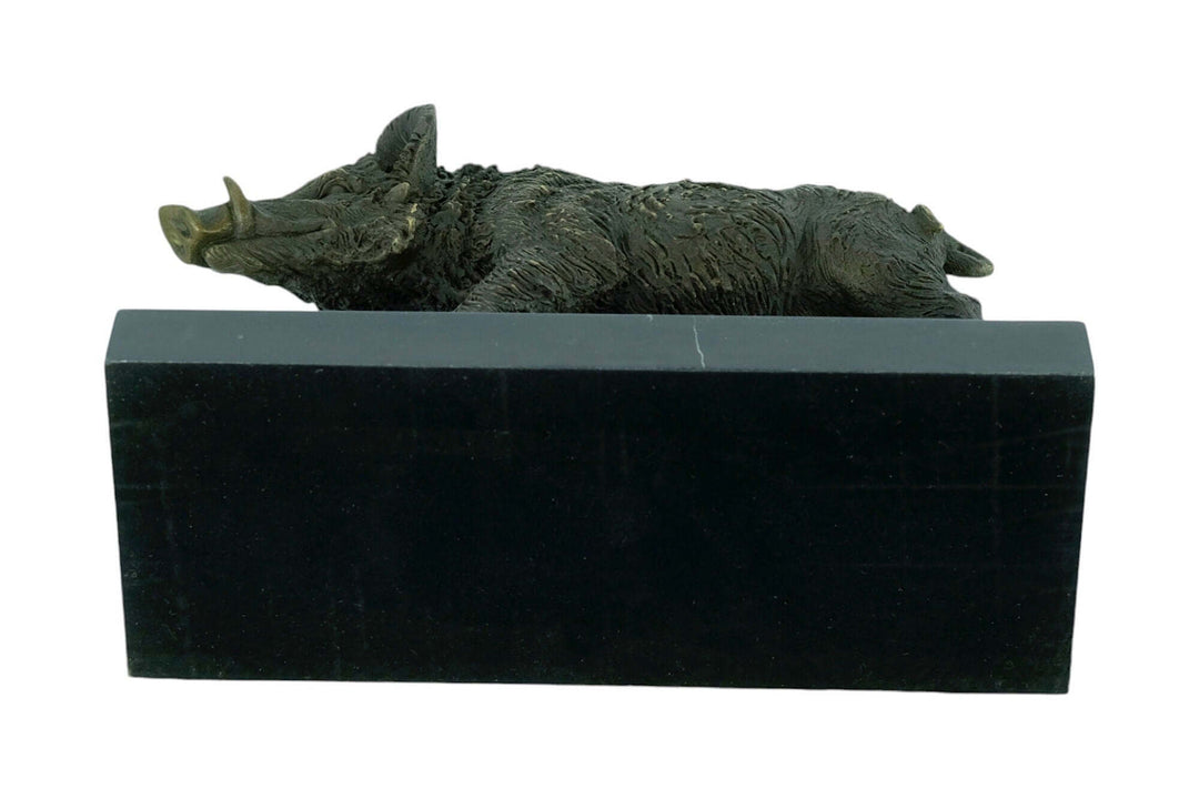 Bronze wild boar sculpture resting on a black marble base, showcasing fine details and warm patina.