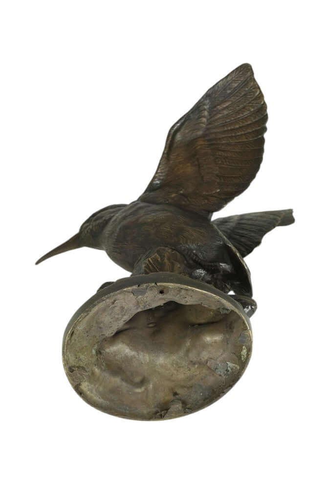 Detailed bronze sculpture of a kingfisher with wings spread atop a decorative tree trunk.