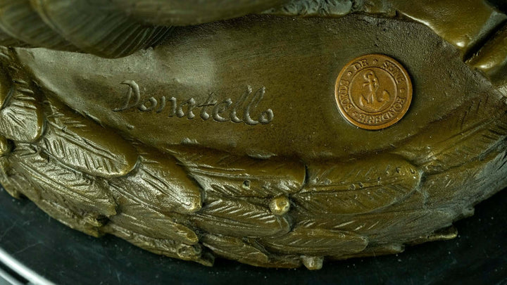 Close-up of bronze sculpture base featuring Donatello's signature and detailed ornate carvings.