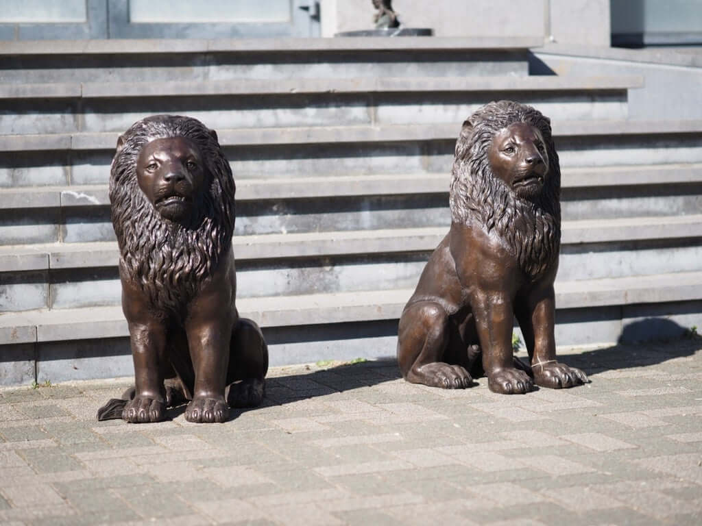 Pair of bronze sitting lion sculptures, elegant guardians for entrance, driveway or garden.