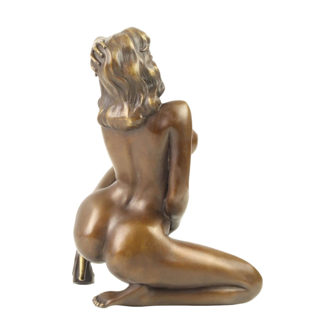 Bronze sculpture of a nude woman captured in a sensual pose, showcasing detailed craftsmanship and warm patina.