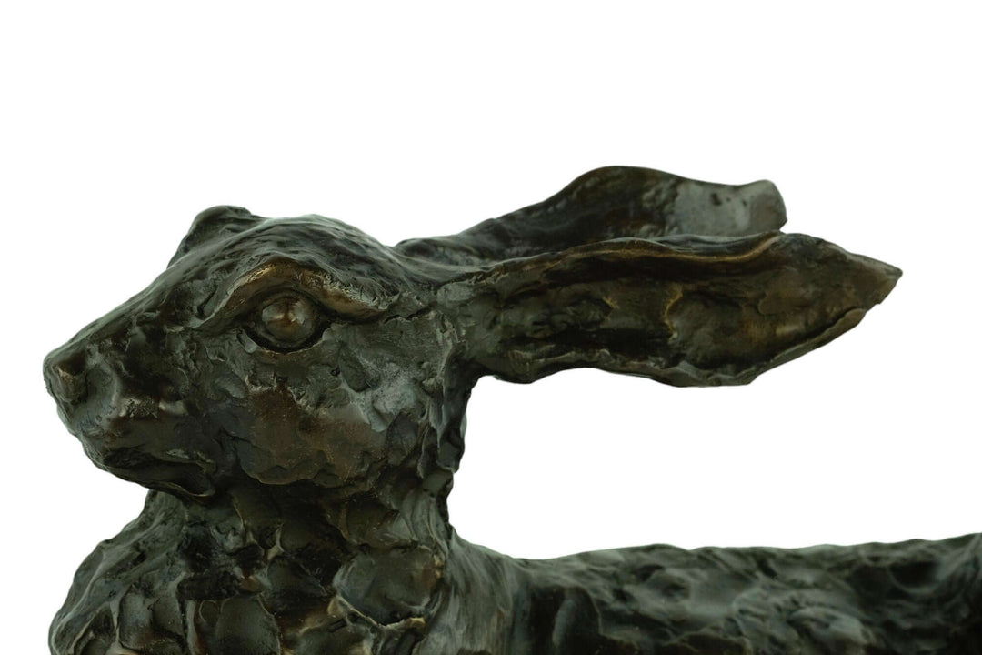 Close-up of a large bronze reclining hare sculpture showcasing intricate detail and warm patina finish.