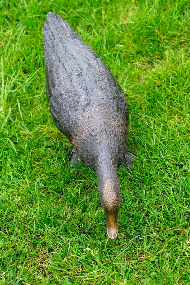 Lifelike bronze sculpture of a foraging duck on green grass, ideal for outdoor display in gardens.