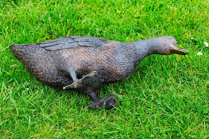 Lifesize bronze sculpture of a foraging duck on grass, beautifully detailed for outdoor decor.