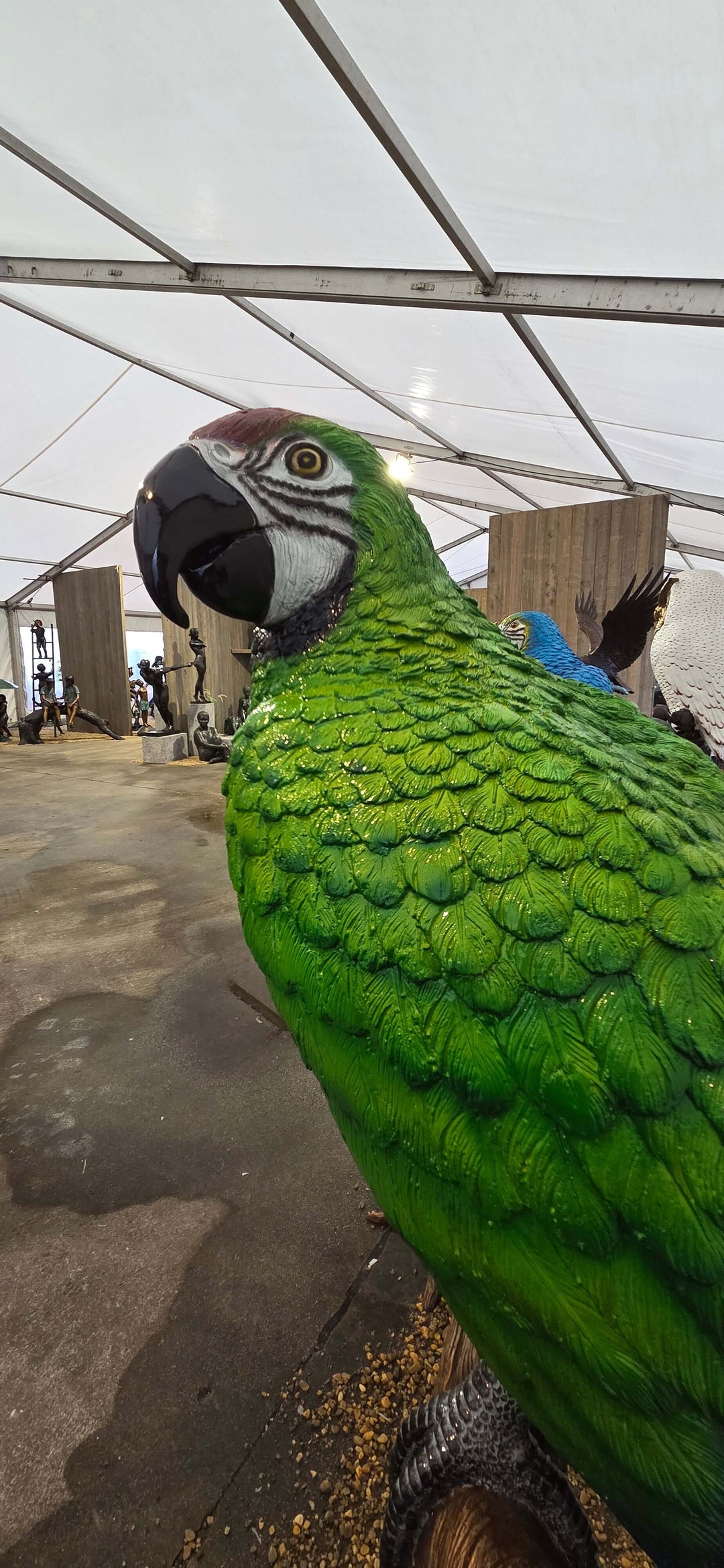 Close-up of a lifesize bronze green macaw sculpture showcasing vibrant details and textures.
