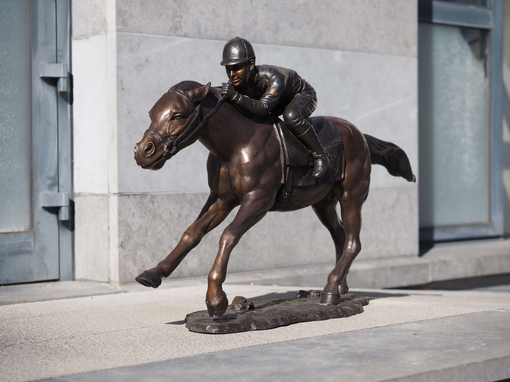 Large bronze sculpture depicting a jockey racing on a horse, showcasing motion and detailed craftsmanship.