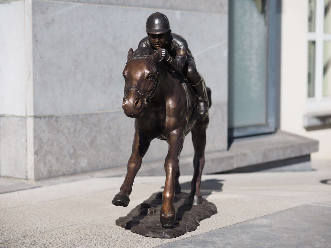 Large bronze sculpture of a jockey racing a horse, showcasing detailed movement and intense focus, perfect for outdoor display.