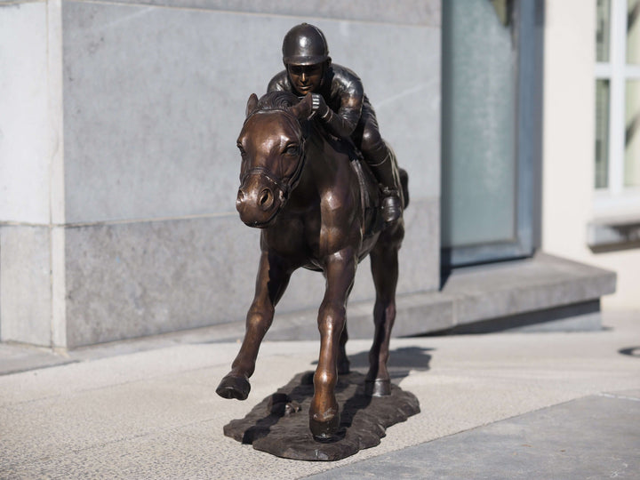 Large bronze sculpture of a jockey racing a horse, showcasing detailed movement and intense focus, perfect for outdoor display.